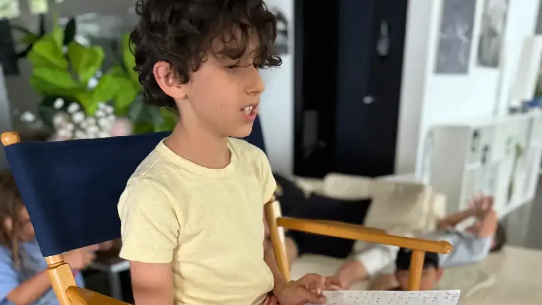 A camper reading his script aloud from the director's chair