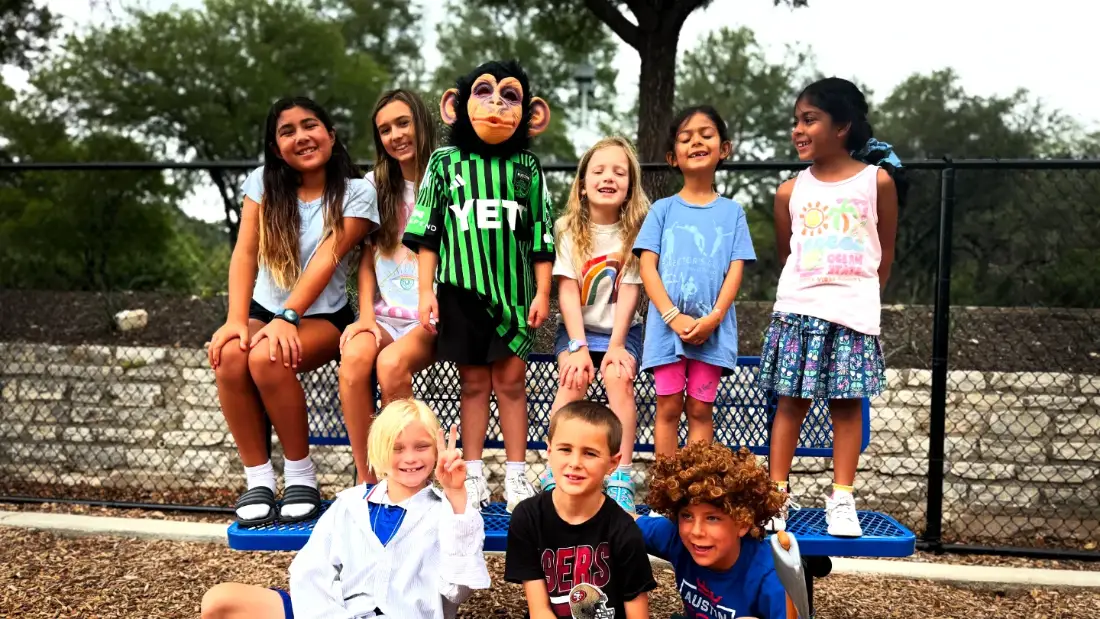 A kids film camp cast in costume outside between setups