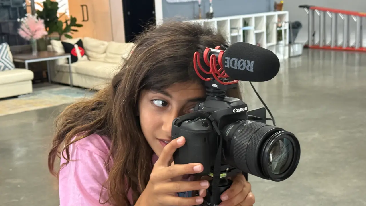 A camper filming a scene on a professional video camera at film camp
