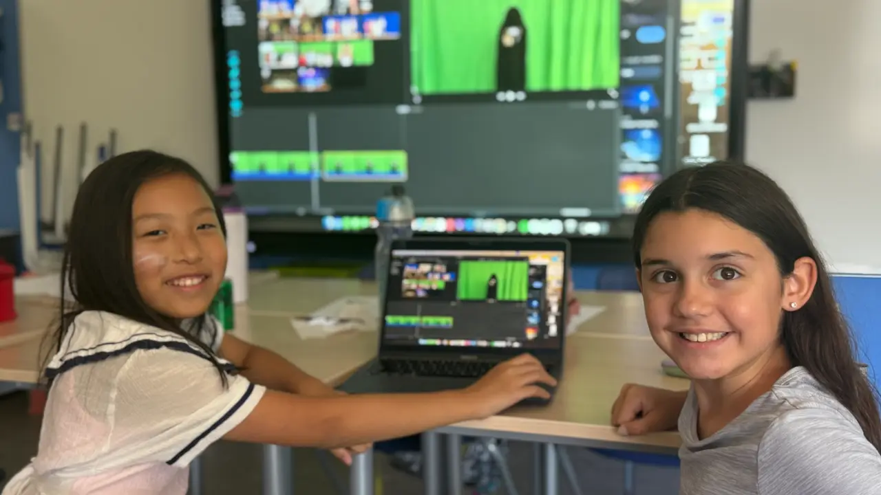 Two campers editing their film on a laptop at a video editing camp for kids