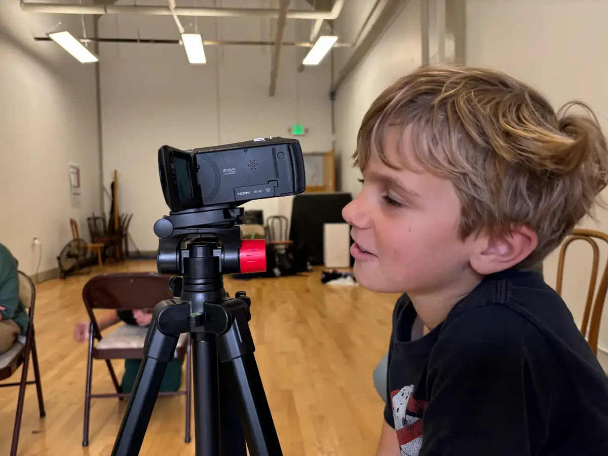 A kid lining up his shot on a professional video camera at filmmaking camp for kids