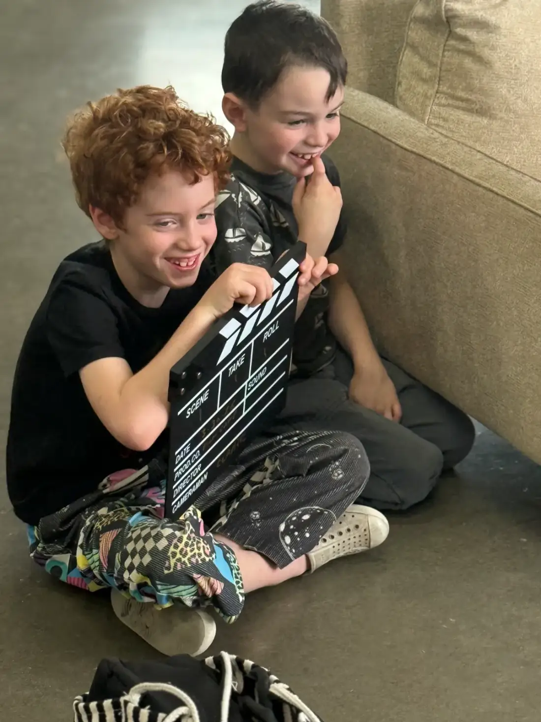 Two campers laughing behind the clapperboard