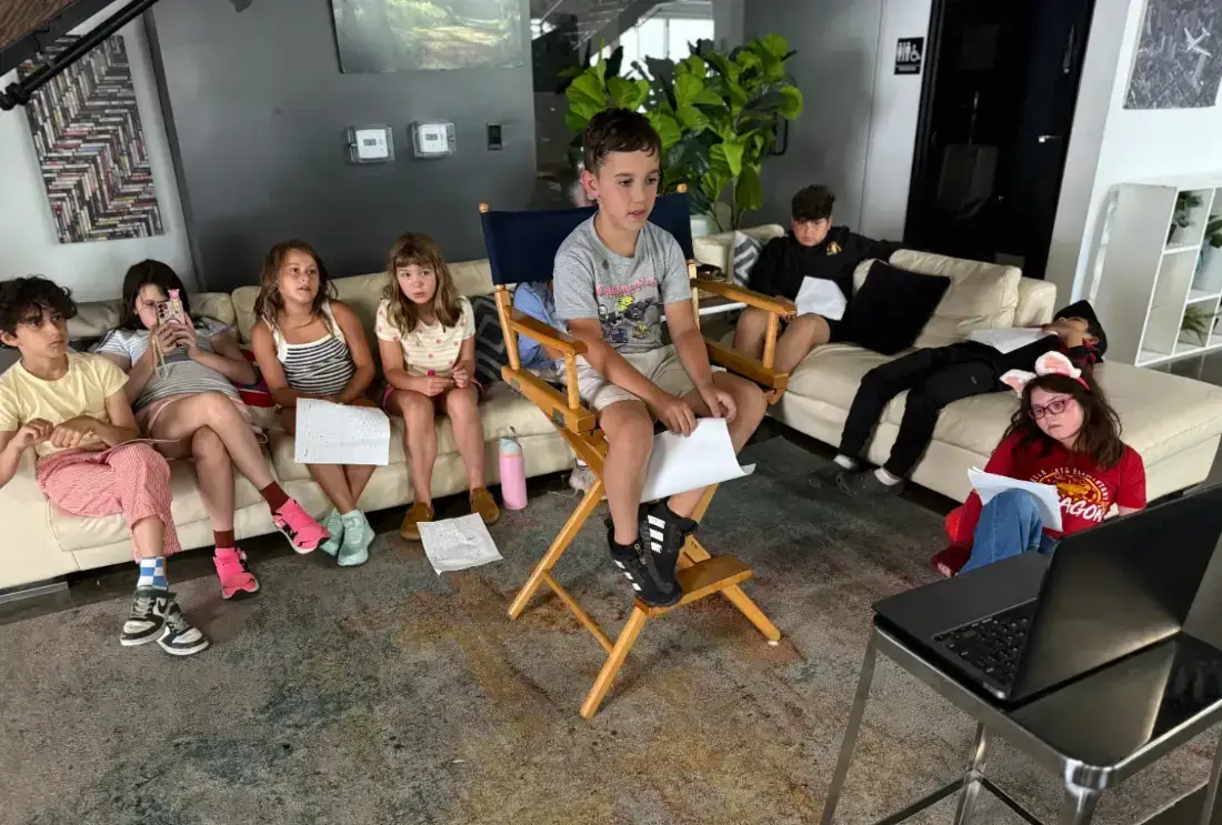 A Sunday class listening as a camper reads his pages from the director’s chair